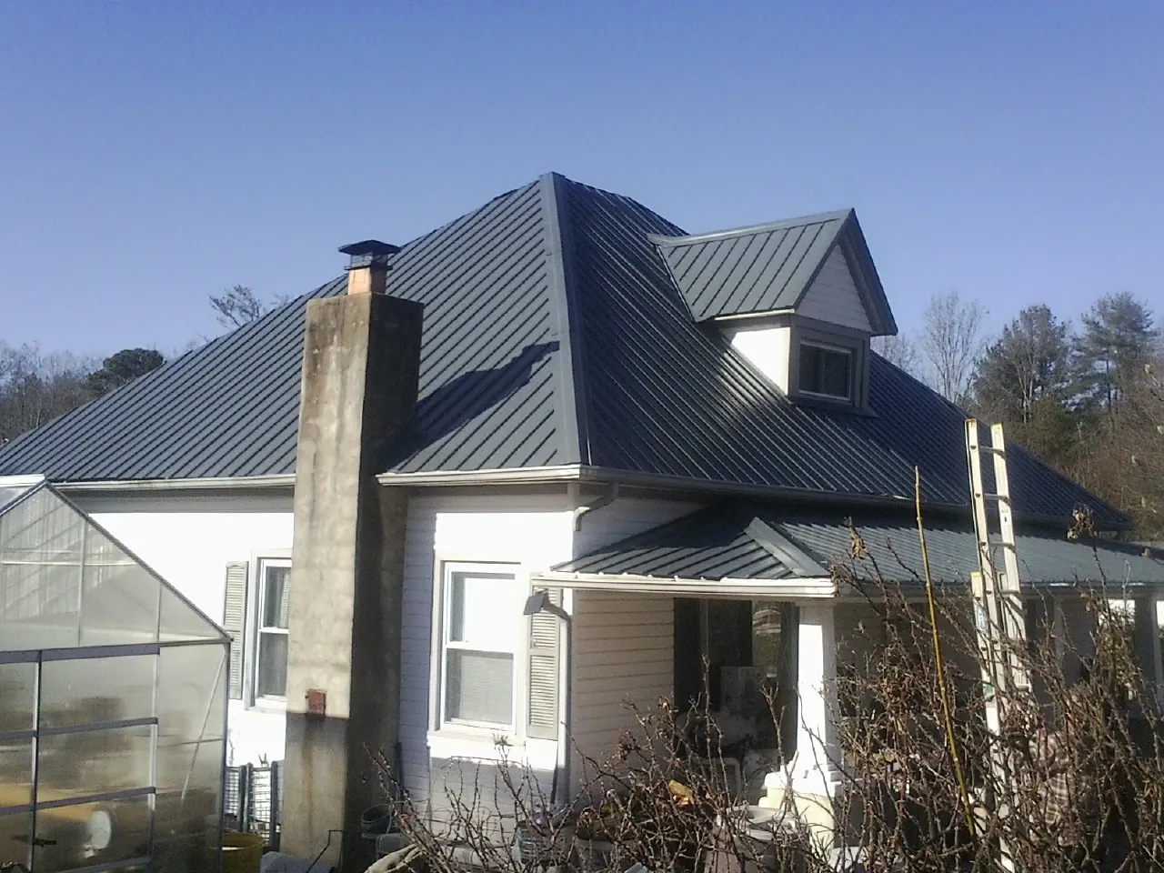 Dark blue standing seam metal roof on a white farmhouse with dormer — Slate & Tile Roof Repair by Roofing Brothers in Mahnomen