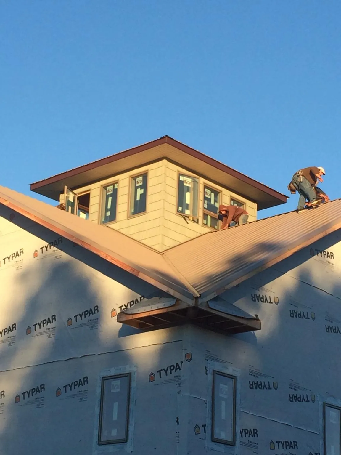 Roofers working around a rooftop cupola on a new metal roof at sunset — Roof Waterproofing in Mahnomen by Roofing Brothers